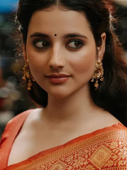 A stunning beauty shot, this close-up captures the model's expressive eyes, flawless skin, and the rich color of her traditional attire.