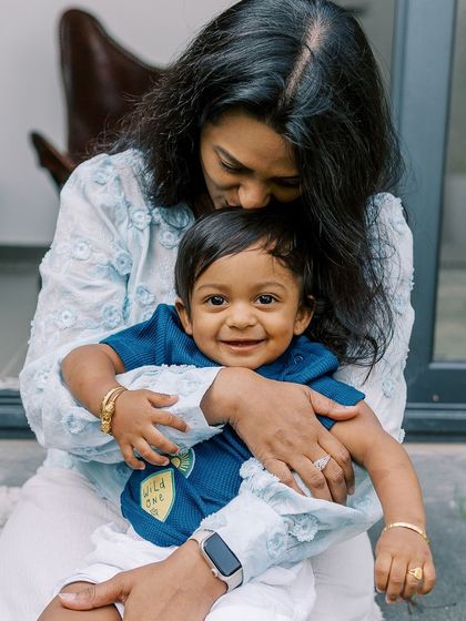 A mother's gentle kiss for her smiling one-year-old. These are the tender moments that truly capture the love in a family.