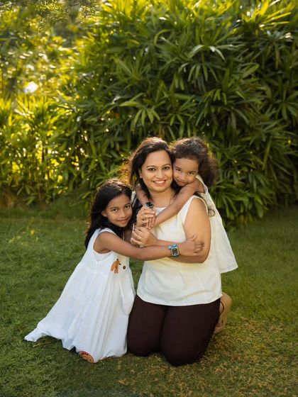 A mother and her two daughters sharing a hug in a sunlit garden. I aim to capture the warmth and love in your family with photos like this.
