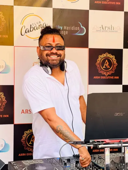 A happy shot of me at my console during a Holi event. You can see the colors on my face and the party branding in the background.