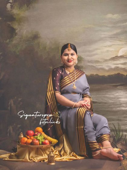 A seated portrait in a grey saree against a painted backdrop, combining traditional elements with a serene mood.