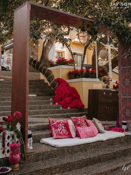 A closer look at the tiered seating, showing the beautiful embroidered cushions and the dramatic red floral arrangements that punctuate the space.