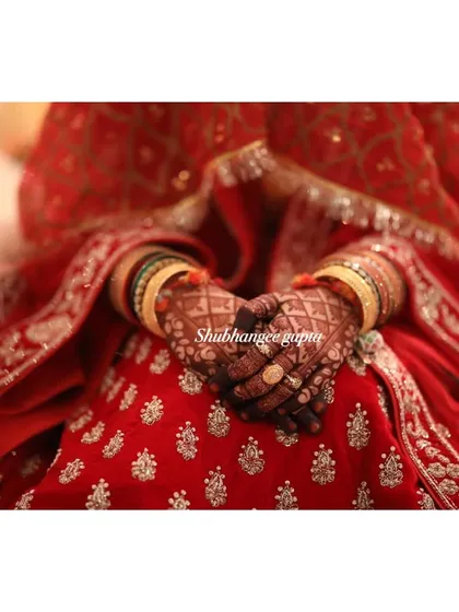 A beautiful shot of a bridal mehndi stain against a red lehenga. The deep maroon color of the henna is a sign of a high-quality, natural paste.