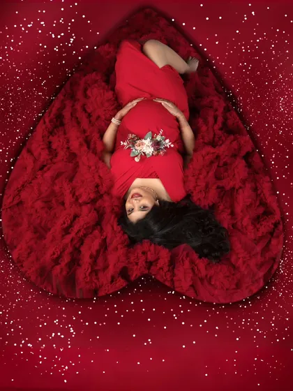 A heart full of love. This creative shot from above frames the mother-to-be within a heart of red fabric, symbolizing the love that surrounds her and her baby.
