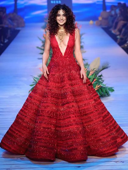A centered, full-length shot of Taapsee Pannu in her stunning red gown. This is a classic runway shot that perfectly documents the designer's creation.