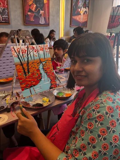A participant with her beautiful autumn river painting. I guide everyone step by step, so even beginners can create a piece they are proud of.
