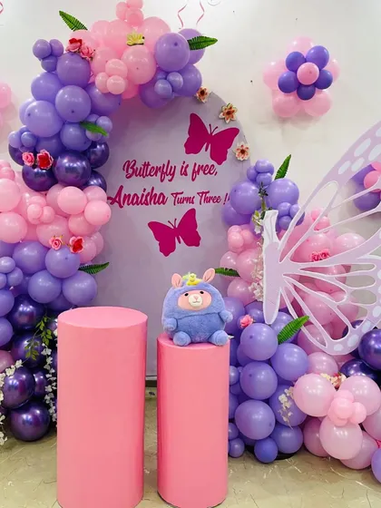 A closer look at the details of this butterfly-themed third birthday, showing the custom backdrop, plush toy centerpiece, and intricate balloon work in pink and purple.