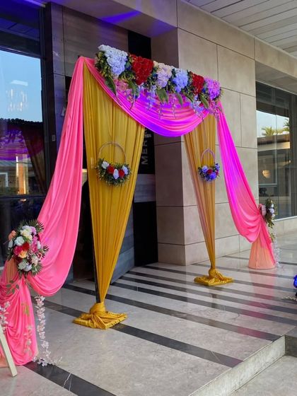 A bright and colorful entrance decoration using pink and yellow drapes, perfect for a daytime event or a Haldi ceremony.
