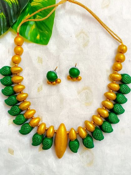 This sleek terracotta choker is made of textured green and gold beads. It's a simple yet elegant design that can be worn for any occasion, and it comes with small matching studs.