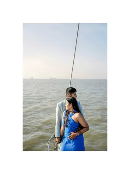 A serene pre-wedding portrait of the couple on a boat off the Mumbai coast. The calm sea and their peaceful embrace create a beautiful, tranquil image.