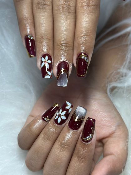 The combination of glossy burgundy, matte white flowers, and gold details creates a rich and luxurious feel.