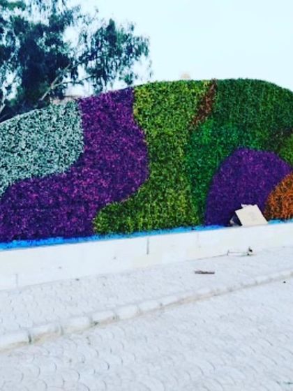 A large-scale custom art installation in the shape of a reclining figure. I used different colors of artificial foliage including green, purple, and orange to create this unique outdoor sculpture.
