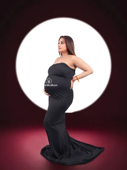 In the spotlight. This dramatic shot uses a single light source to create a theatrical effect, highlighting the beautiful silhouette of the mother-to-be in a classic black gown.