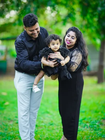 A perfect family moment captured outdoors. We love creating natural and candid family portraits, like this one of a mother and father lovingly holding their toddler against a lush green background. These sessions are all about genuine interaction and joy.