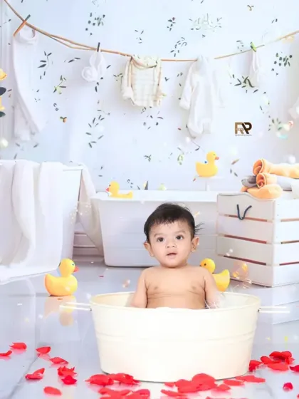 A half-birthday celebration with a fun splash session. The "1/2" sign adds a unique touch to this shot of a baby enjoying a bath with rose petals and bubbles.