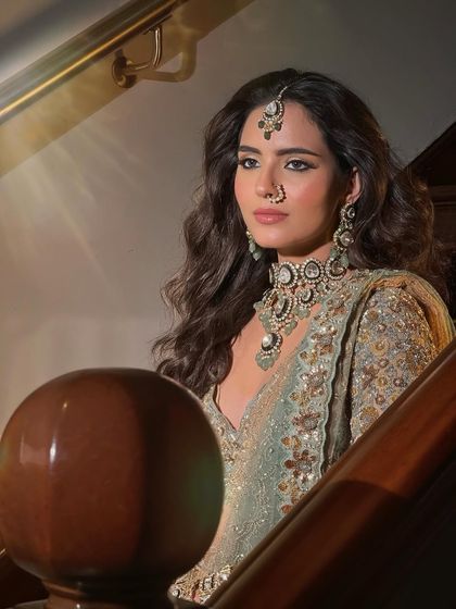 A striking portrait of the bride on a staircase. The lighting creates a dramatic effect, highlighting her powerful and elegant look.