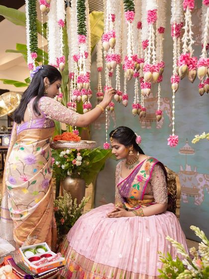 A family member blesses the bride during a pre-wedding ritual. The decor, with its hanging flowers and traditional elements, creates a sacred space that honors these heartfelt moments.