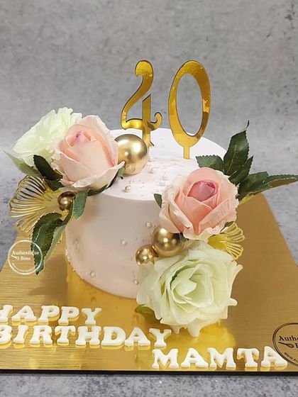 An elegant ginkgo floral cake for a 40th birthday. The soft pink cake is adorned with fresh roses and golden ginkgo leaf accents.