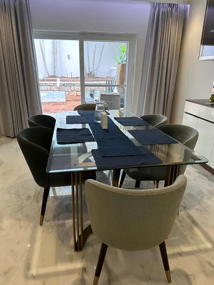 A glimpse into a beautiful residence featuring our custom dining set. The glass-topped table with its sculptural metal base and the elegantly curved dining chairs are tailored to the client's sophisticated taste.