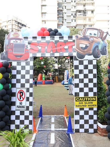 A wider view of the 'Cars' themed entrance arch, with traffic light balloon columns and checkered flag details. Every element is carefully planned.