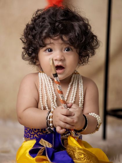 A close-up portrait of a baby Krishna with his flute and beautiful pearl necklaces. I focus on capturing these innocent, curious expressions that make each photo a unique treasure.