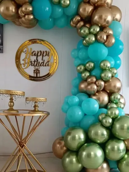 This balloon arch in shades of teal, green, and gold adds a touch of elegance to any home party. Paired with gold cake stands, it creates a beautiful and cohesive dessert table display.