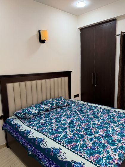 A simple and elegant bedroom with a dark wood bed featuring a cream-colored upholstered headboard and a matching wardrobe.