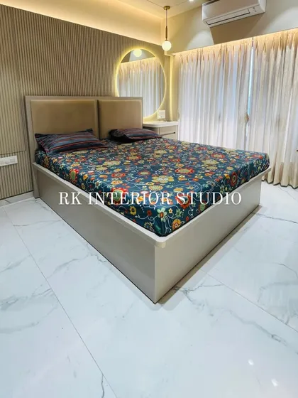 A beautifully designed master bedroom with a full-height wardrobe and a bed with a custom back panel. The round mirror with a cove light above the dressing table adds a modern, stylish touch.