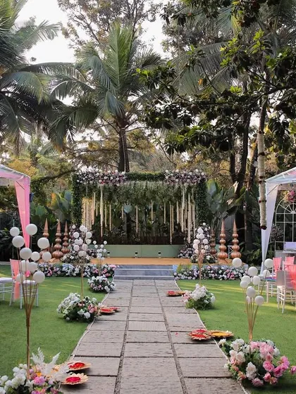 A wide view of a beautiful wedding setup on our main lawn. This shows the scale of the space, with guest seating arranged on either side of the stone aisle, all framed by towering trees.