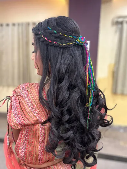 A full view of the glamorous and playful Mehendi hairstyle. The soft waves combined with the colorful threads create a beautiful and unique look.