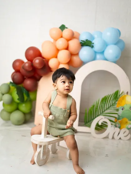 A portrait from a jungle-themed first birthday shoot, complete with a wooden tricycle and colorful balloon arch. I provide a variety of props to make every session unique.