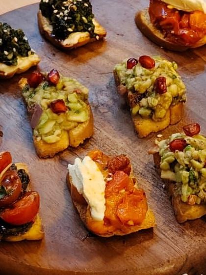 An assortment of our artisanal bruschetta, featuring toppings like avocado with pomegranate, spinach and cheese, and classic tomato with basil. A perfect, versatile appetizer.