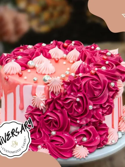 A passionate anniversary cake with vibrant red and pink buttercream roses and a drip effect. This bold design is perfect for celebrating a fiery romance.