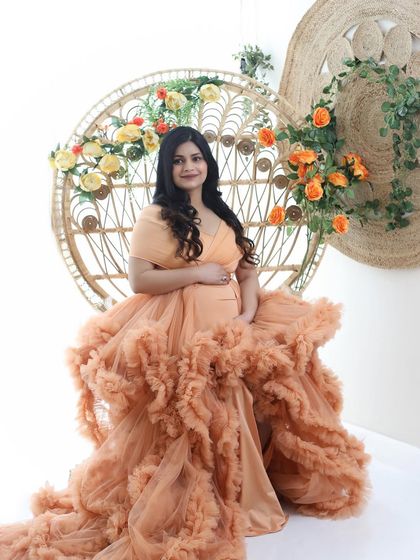 Daydreaming of the new chapter ahead. This mom-to-be looks ethereal in a voluminous peach gown, seated on a peacock chair decorated with flowers.