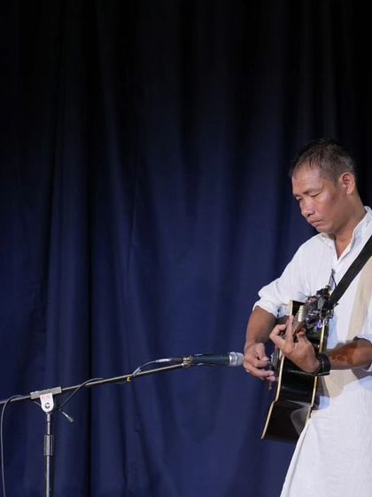 A teacher accompanying students on guitar during a traditional music segment.