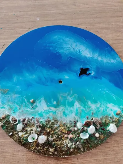 This completed resin art piece shows the beautiful blending of turquoise and white to create ocean foam, with a sandy shore made of real shells.