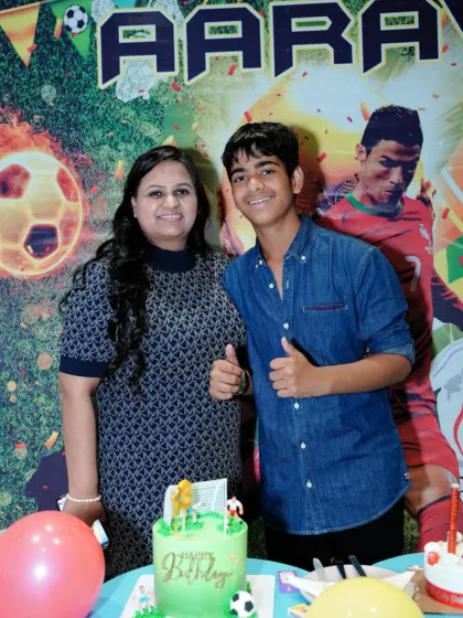 A proud mother and her son celebrate his birthday with a football-themed cake.