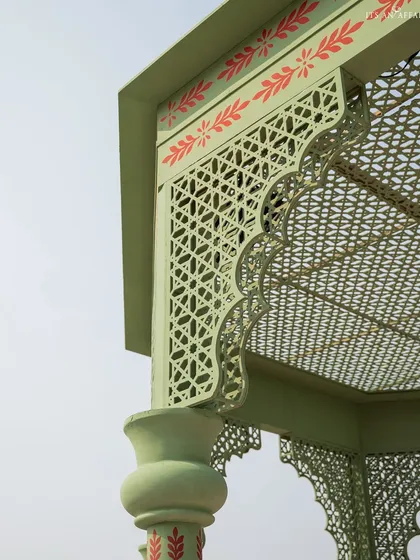 A close-up of the intricate jali cutwork and hand-painted motifs on the mandap structure. These details are inspired by the architectural elements of Mughal palaces.