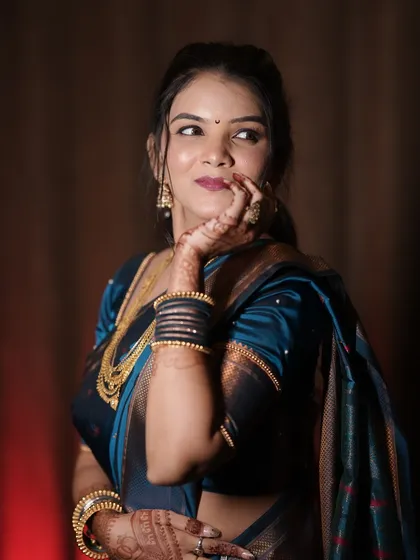 A playful, glamorous shot of the bride. The lighting highlights her contour and the rich color of her teal saree.