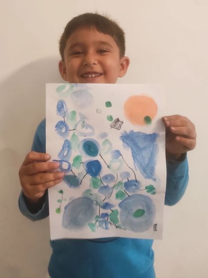 A student proudly displays his magical watercolor creation, full of beautiful strokes and colors.
