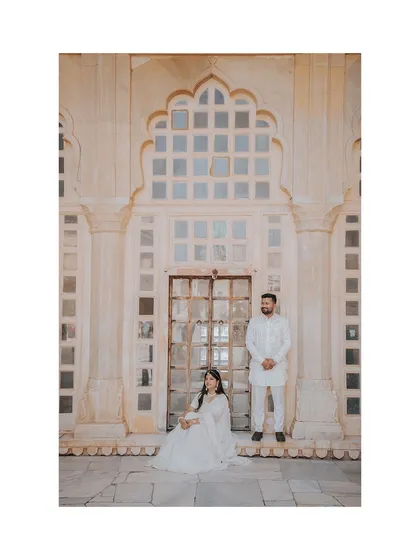 A regal portrait of the couple posing in front of a jali window at Amer Fort, creating a classic and elegant image.