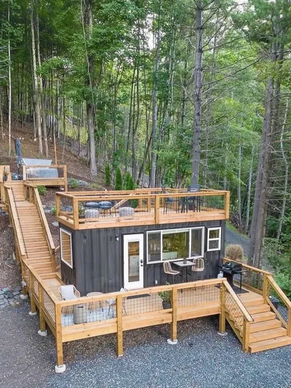 This multi-level container home is perfect for a hillside location. The extensive decking, rooftop terrace, and integrated hot tub create multiple outdoor living areas, maximizing space and enjoyment.
