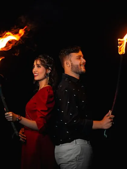 Back to back, with torches lighting up the darkness. This shot is full of adventure and drama, perfect for a couple that loves a bit of flair.