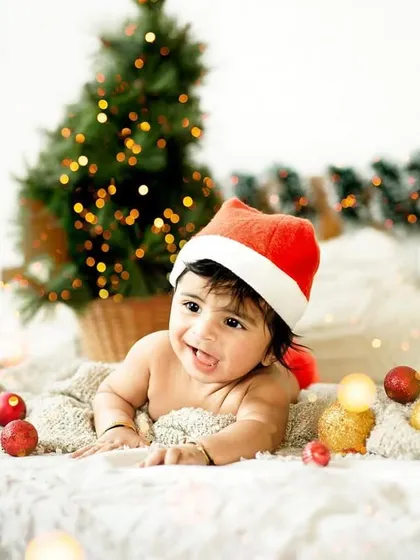 A happy baby enjoying our cozy Christmas setup. Wearing a Santa hat and surrounded by festive lights, his smile is infectious and full of holiday cheer.
