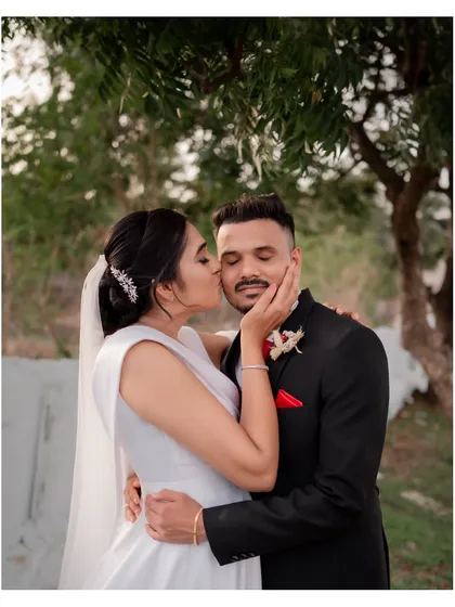 A sweet and candid moment after the ceremony, with the bride planting a happy kiss on her groom's cheek.