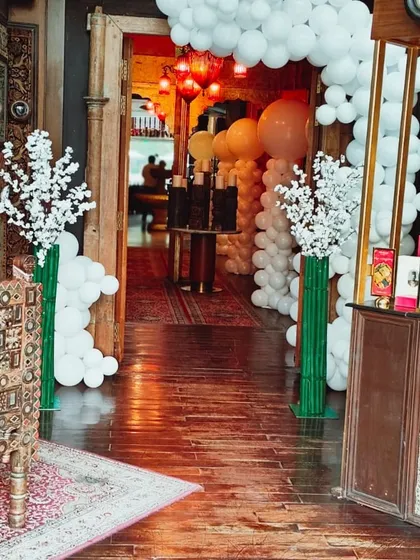 A welcoming entrance decorated in a white theme, with white balloon garlands and cherry blossom arrangements.