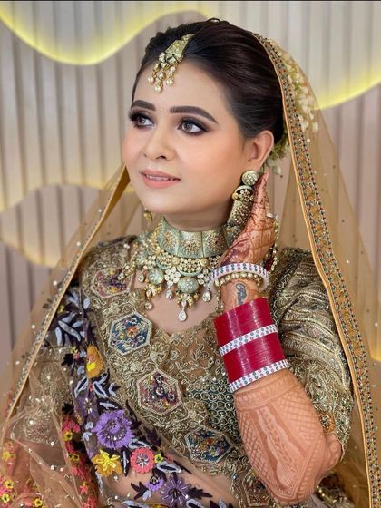 A beautiful bride in a pastel lehenga, wearing a classic kundan choker set.