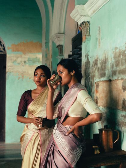 Two dancers share a moment over a glass of water. The setting, with its peeling paint and old-world charm, provides an authentic backdrop for this story of artists.