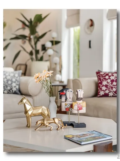 A close-up of the coffee table at Casa D Umravi, showcasing a collection of unique decor items. The geometric brass horse and stylized wooden figures add an artistic and personal touch to the living space.