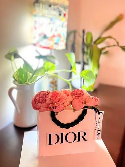 A chic and fashionable Dior shopping bag cake. This sculpted cake is perfect for a luxury brand lover, complete with edible tissue paper flowers peeking out of the top.